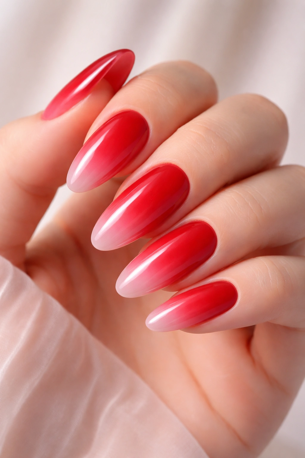 Close-up of long rounded nails with red-to-pink ombre gradient