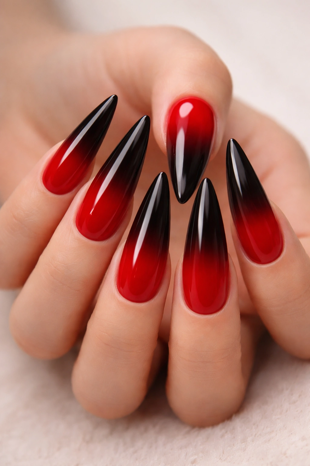 Close-up of long stiletto nails in a red-to-black ombre gradient