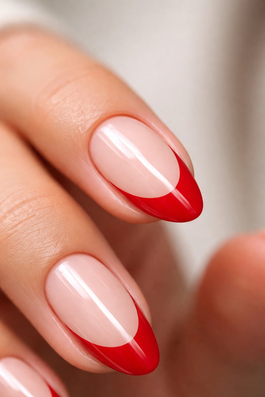 Close-up of short almond nail with dense red French tip over nude base