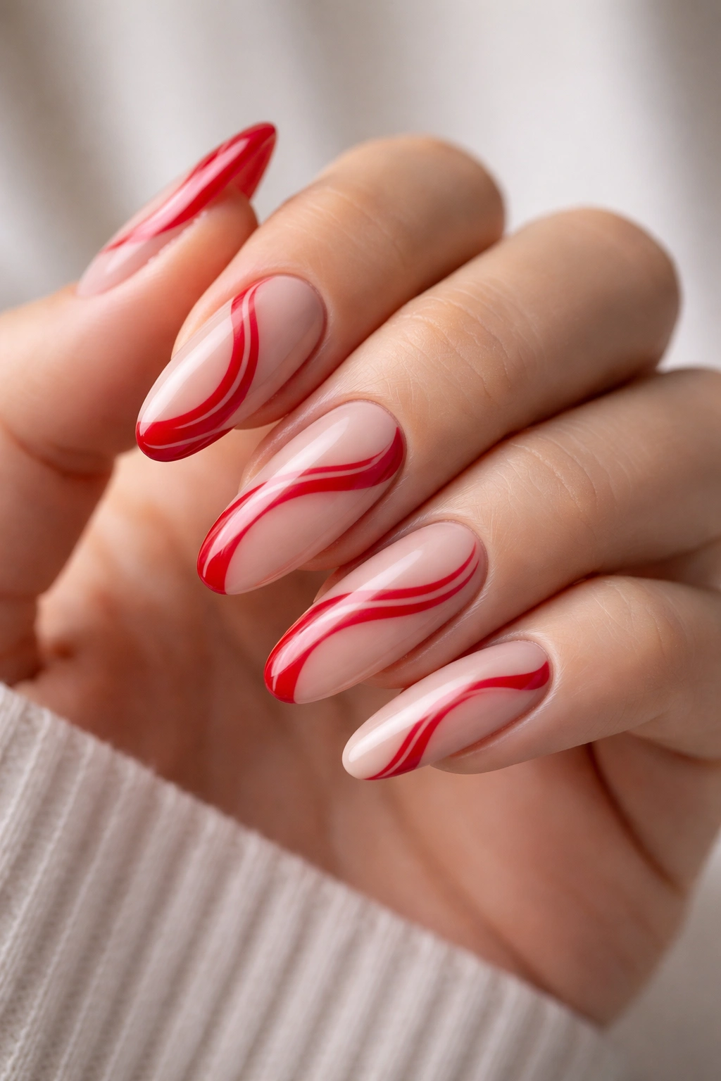 Close-up of red and nude swirl nails on long oval nails with negative space