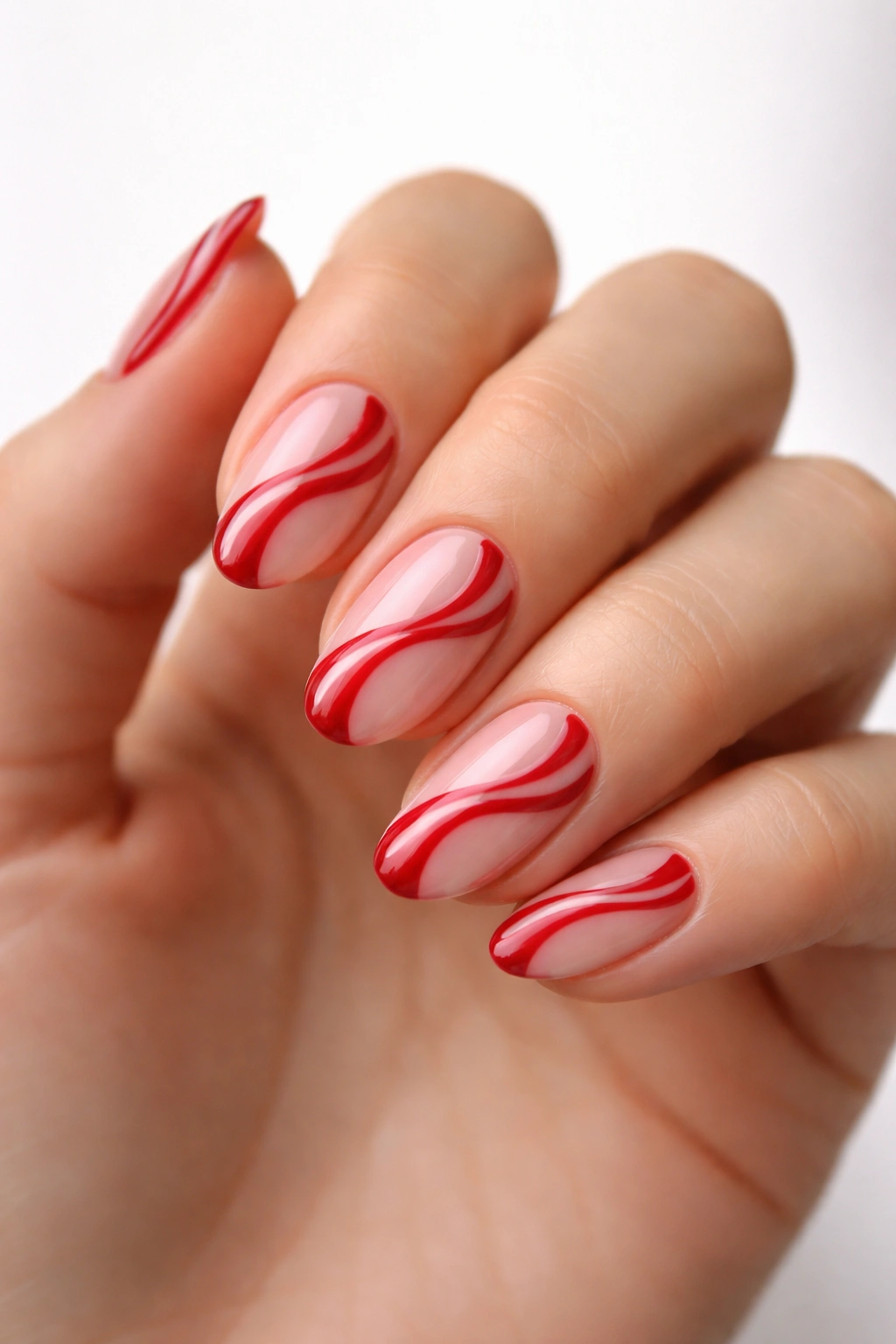 Close-up of short almond nails with red swirl designs on a sheer base