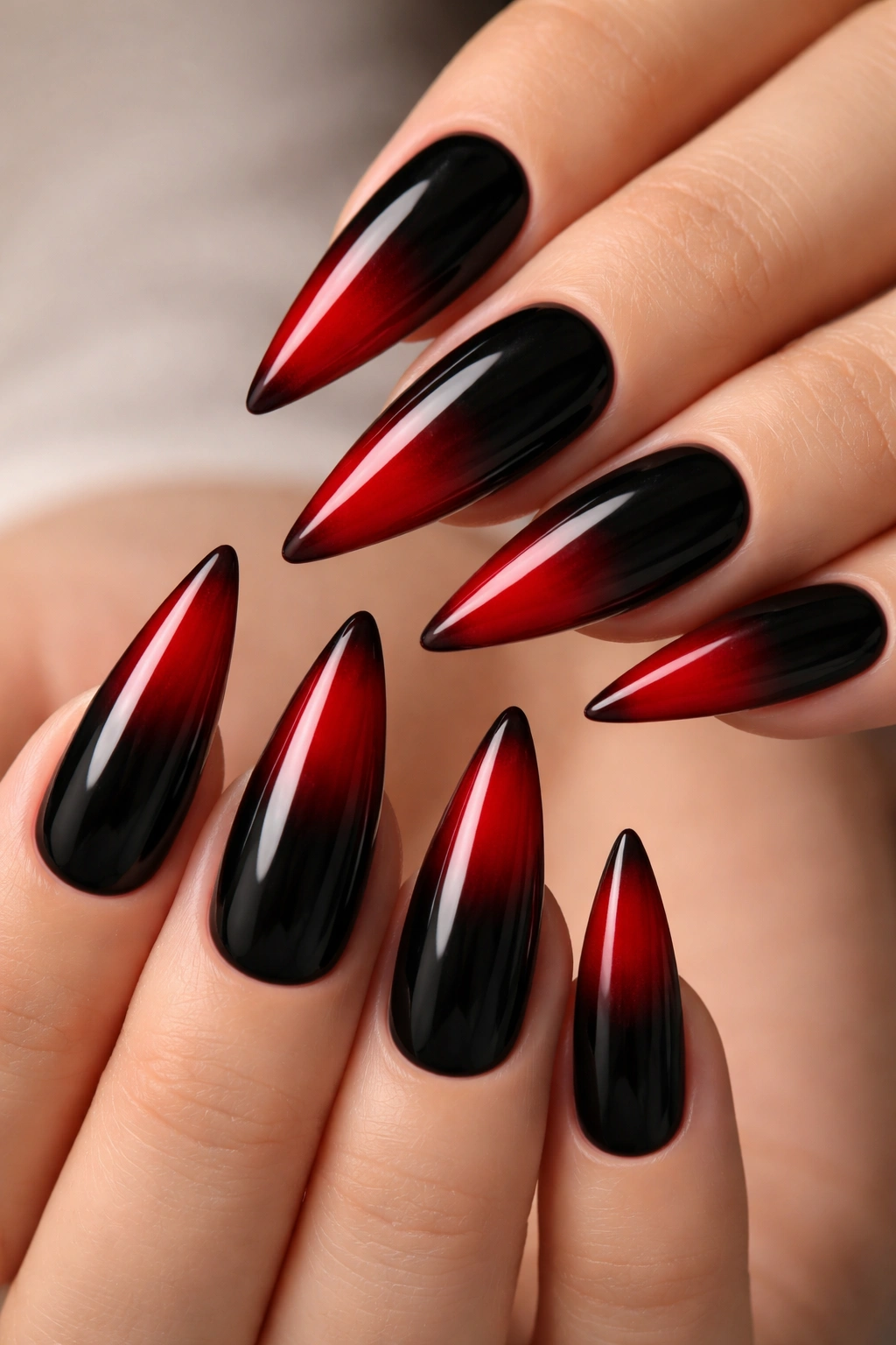 Close up of black base stiletto nails with red ombre French tips