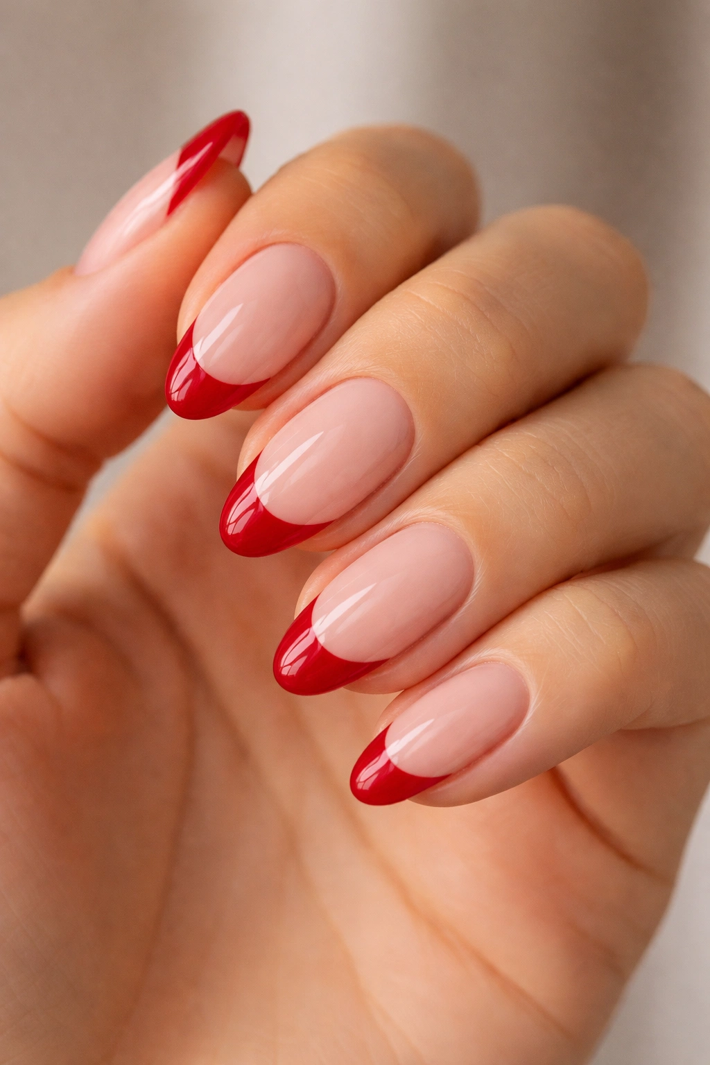 Close-up of short almond nails with red tips on bare natural base