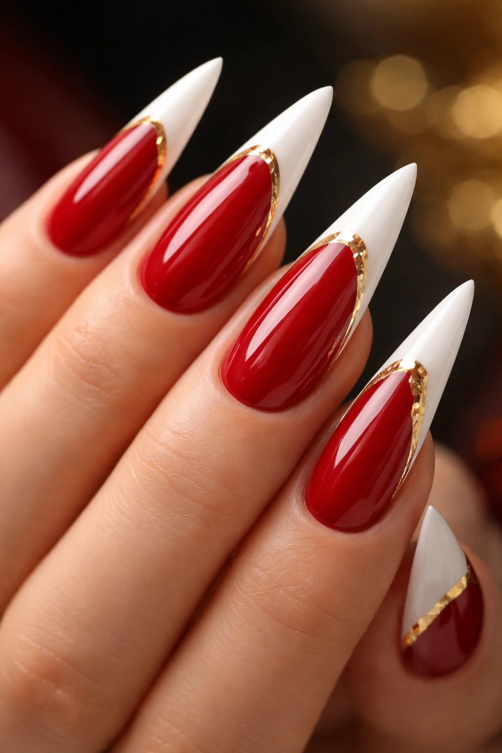 Close-up of red and white stiletto nails with gold accents