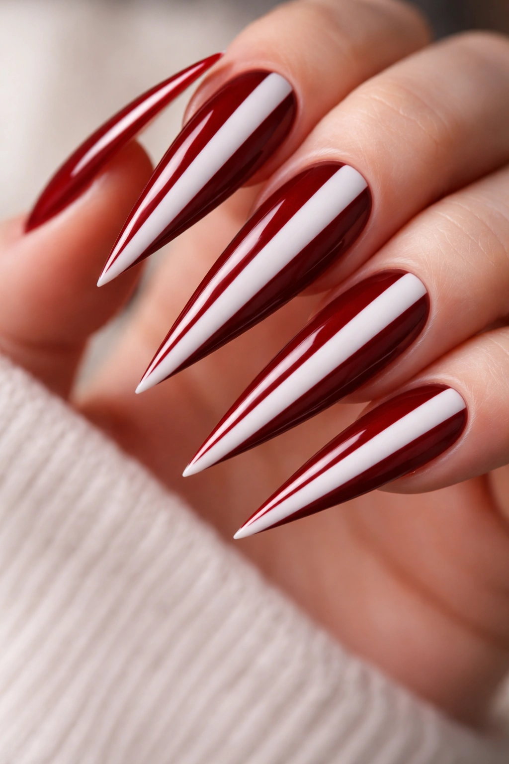 Close-up of dark red and white striped stiletto nails.