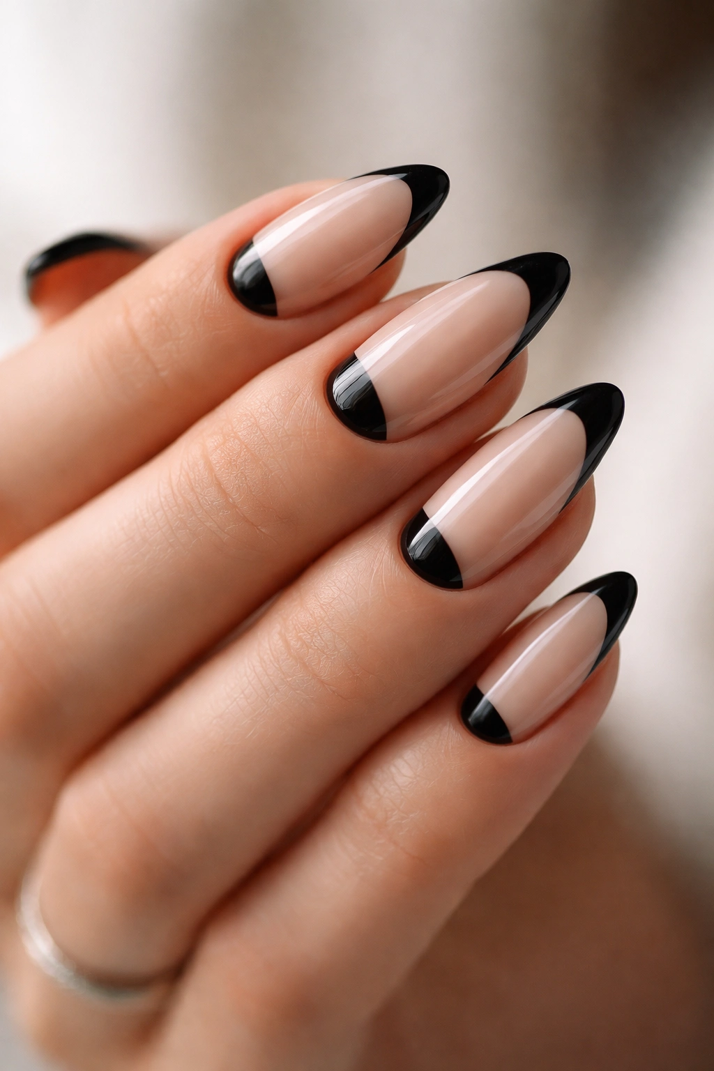 Almond nails with reverse black French tips near the cuticle, nude base.