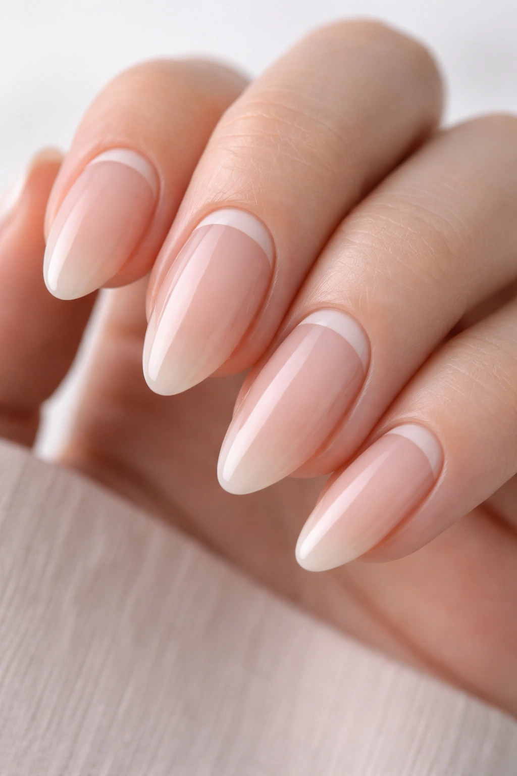 Almond nails with a near-cuticle reverse French line in soft neutral tones.