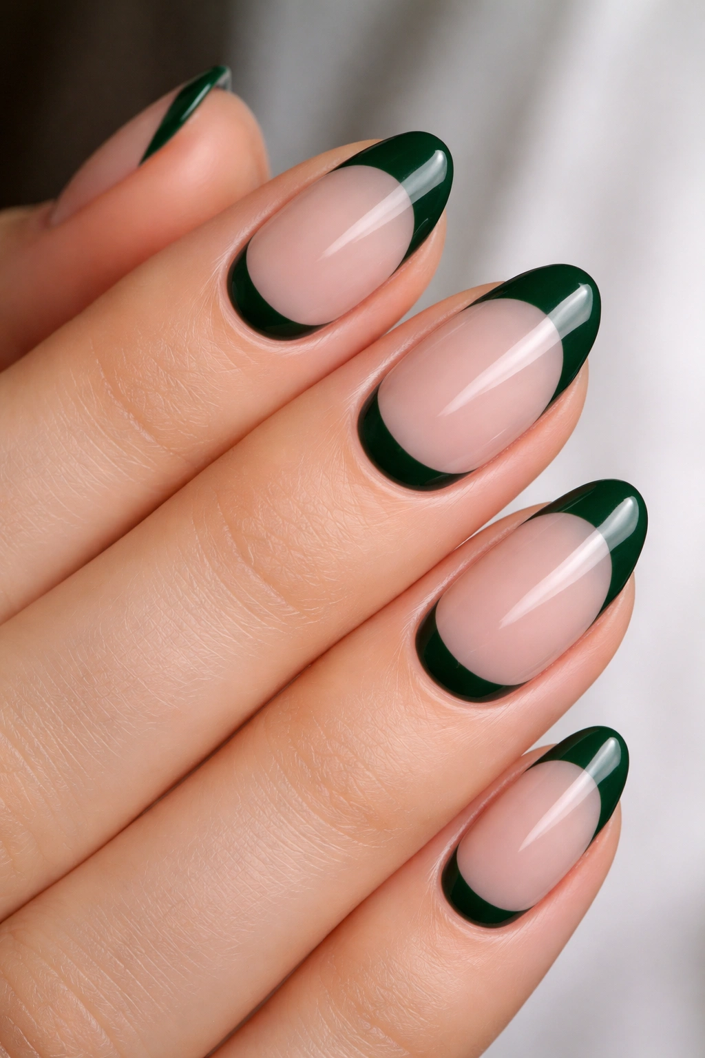 Close-up of short almond nails with a dark green cuticle base crescent
