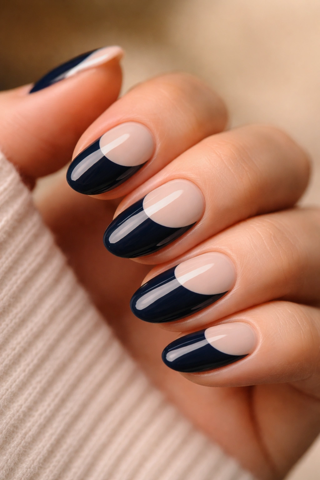 Close-up of short almond nails with navy base and pale tip