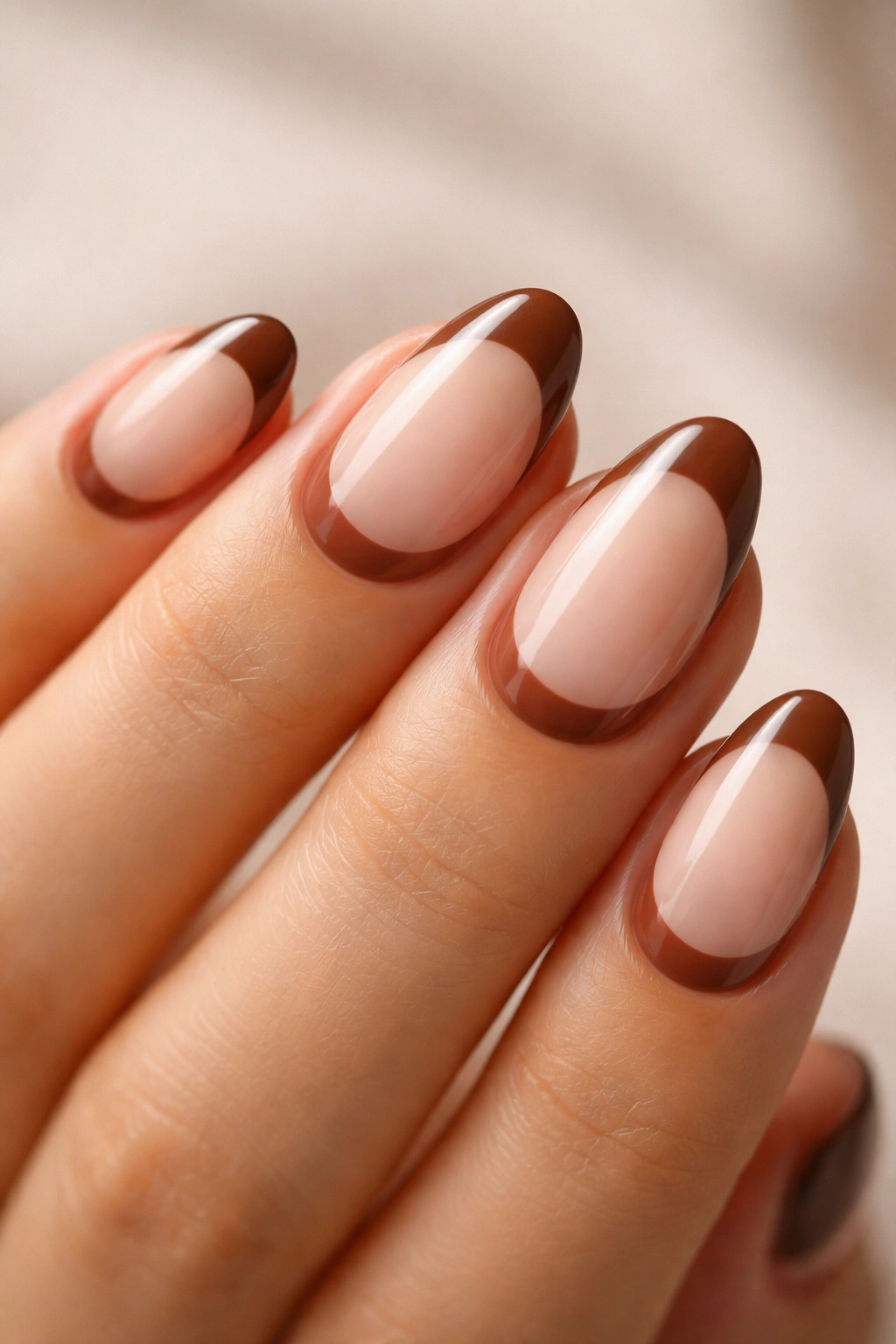 Close-up of a short almond nail with brown crescent at cuticle on nude base