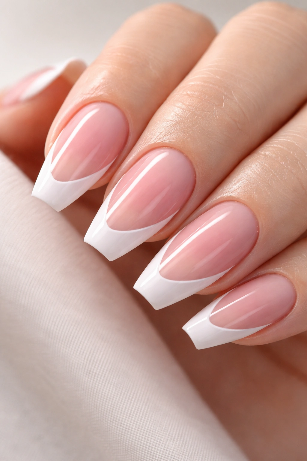 Close-up of reverse duck nails with wide-base French tips fading to nude tip on neutral backdrop