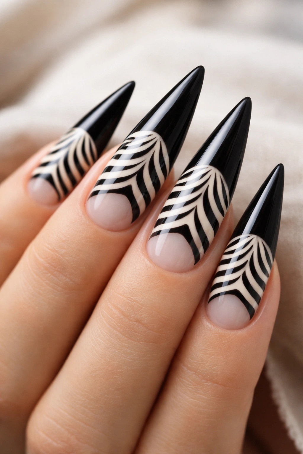 Stiletto nails showing striped base transitioning to solid tip with negative space