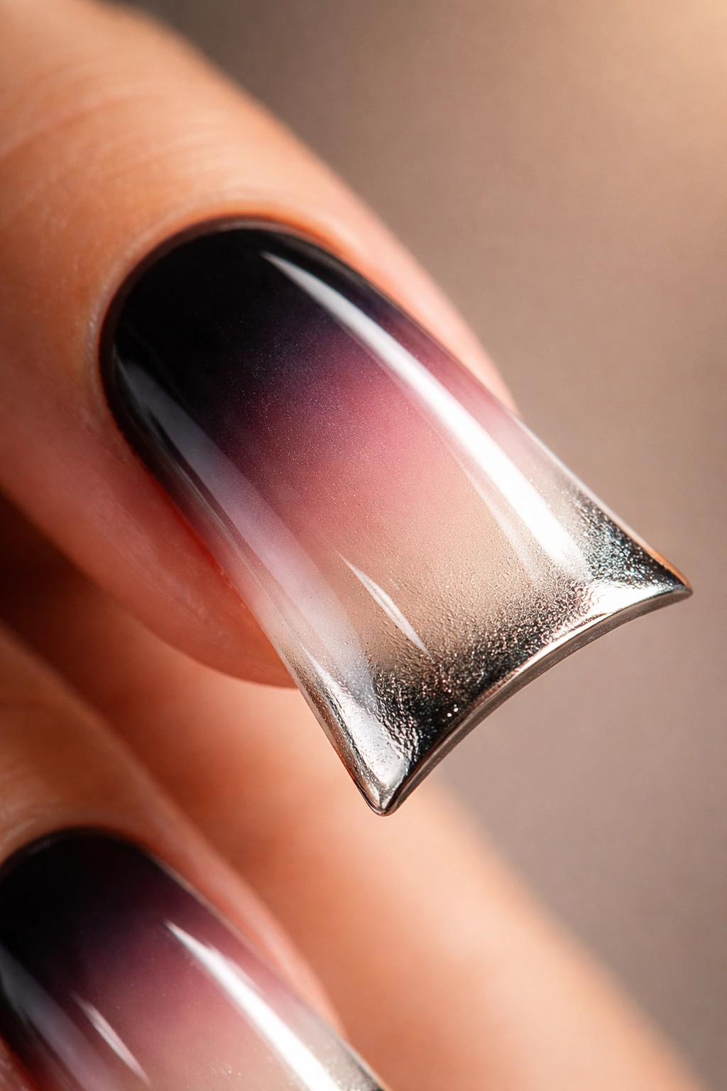 Duck nail showing reverse ombre with a metallic tip on a neutral background