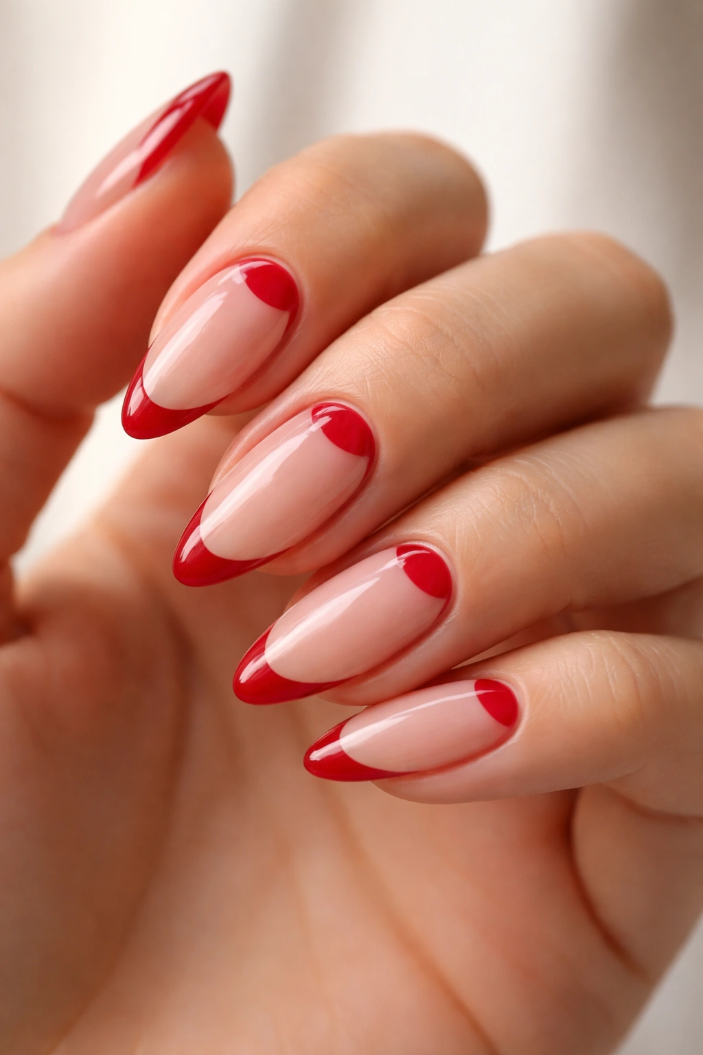 Close-up of almond nails with reverse red French tips at the base