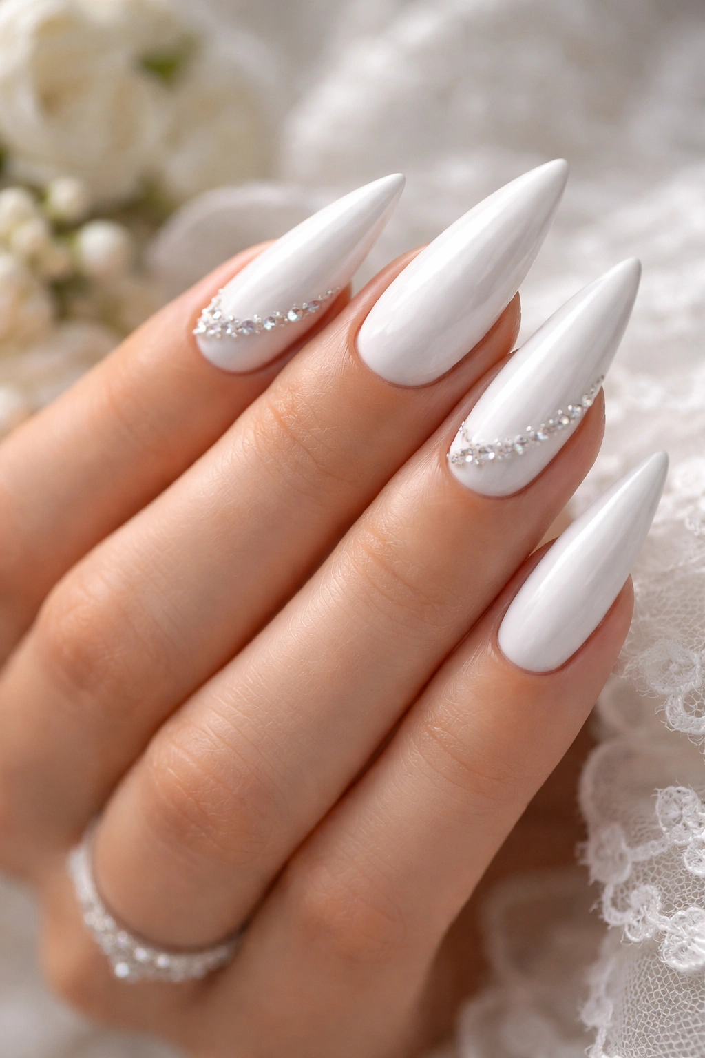 White stiletto nails with understated rhinestone accents