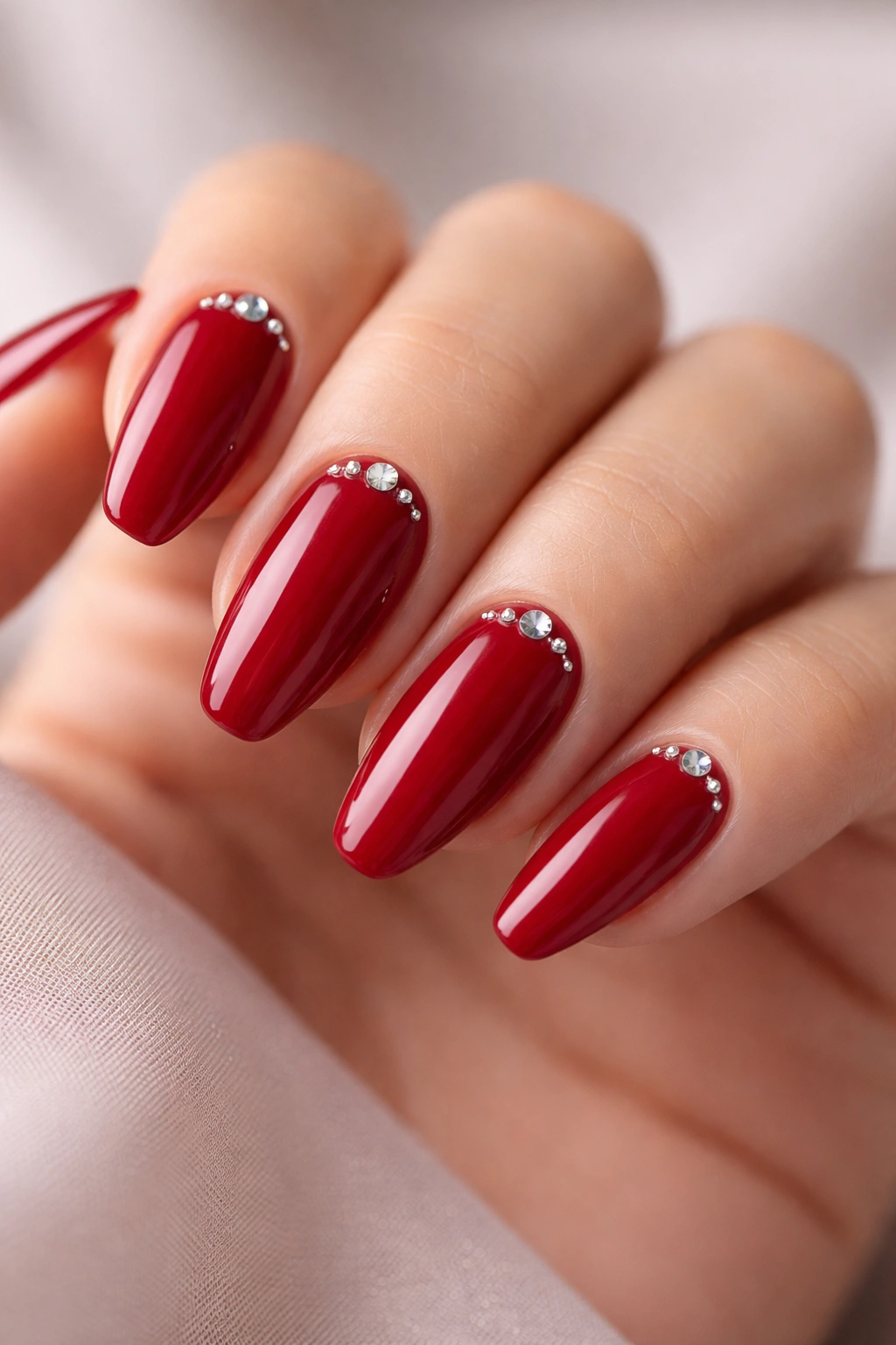 Close-up of red nails with small rhinestones along the cuticle.