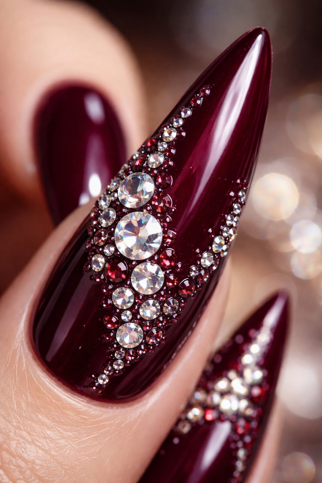 Macro close-up of burgundy stiletto nail with precisely placed rhinestones