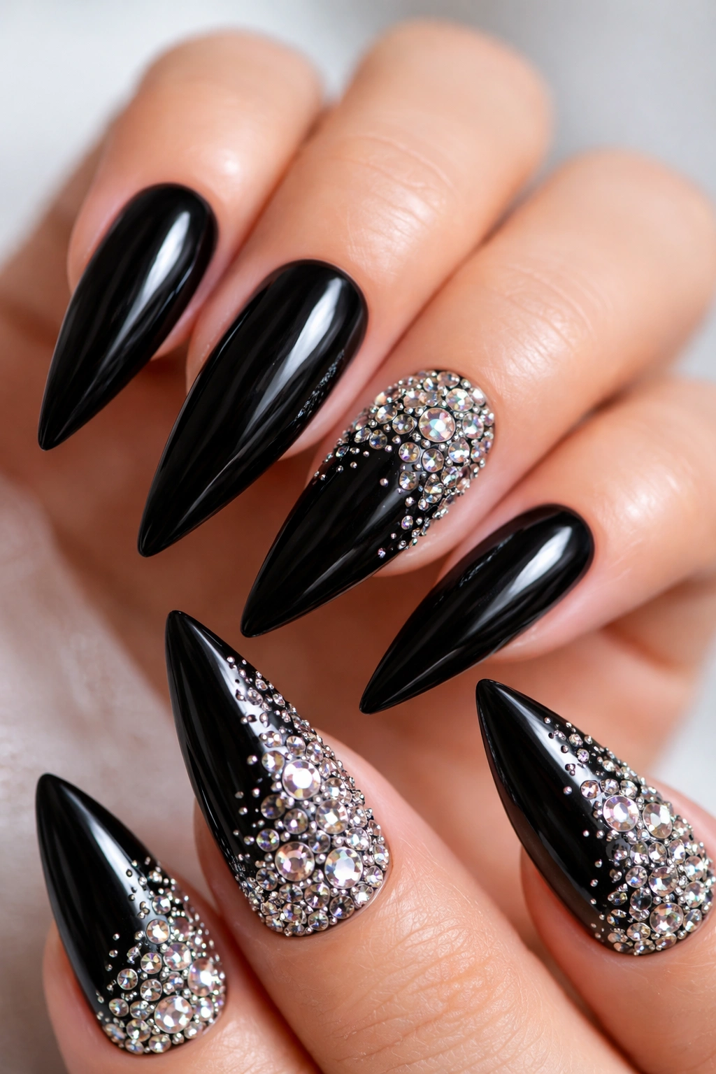 Black stiletto nail with rhinestones concentrated at corner fading outward