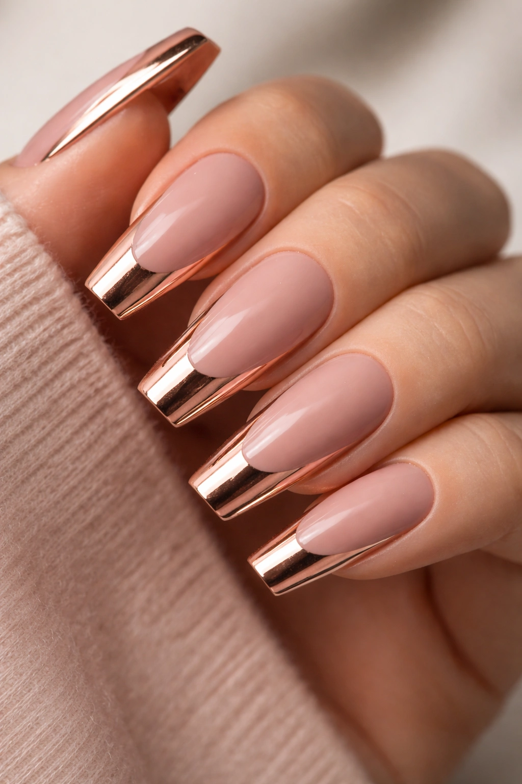 Close-up of rose gold coffin nails with matte base and glossy tip on a hand