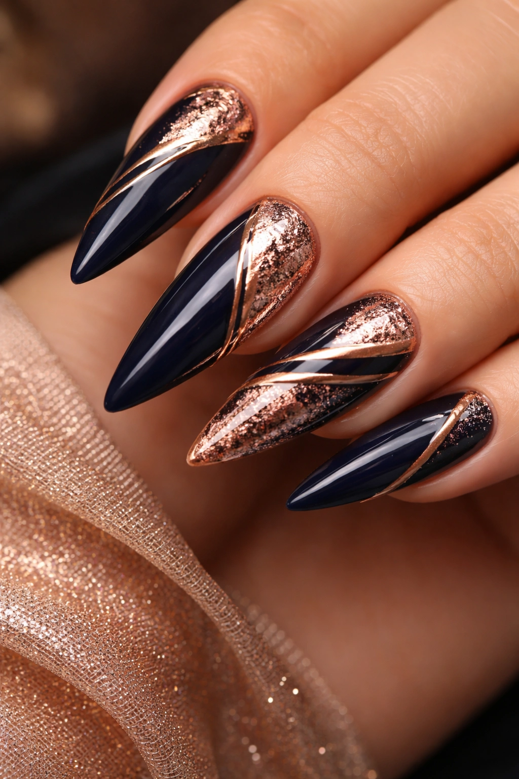 Dark blue nails with rose gold accents in stripes or foil