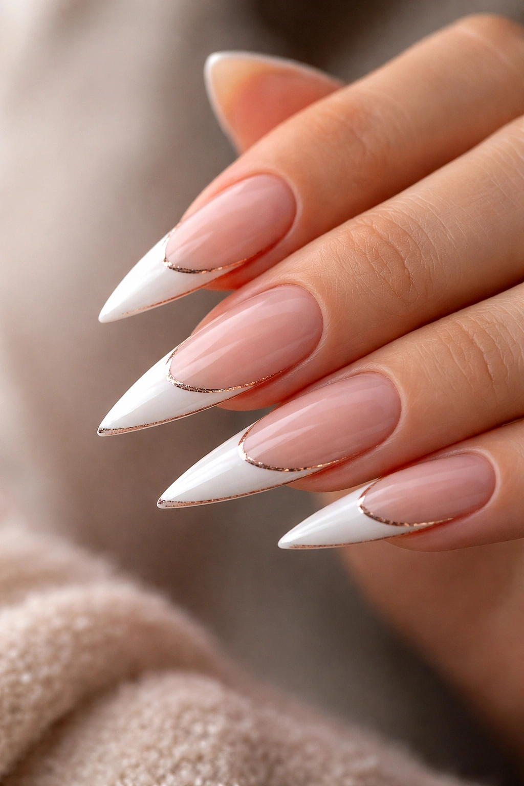 Close-up of stiletto nails with white tips and rose gold edge
