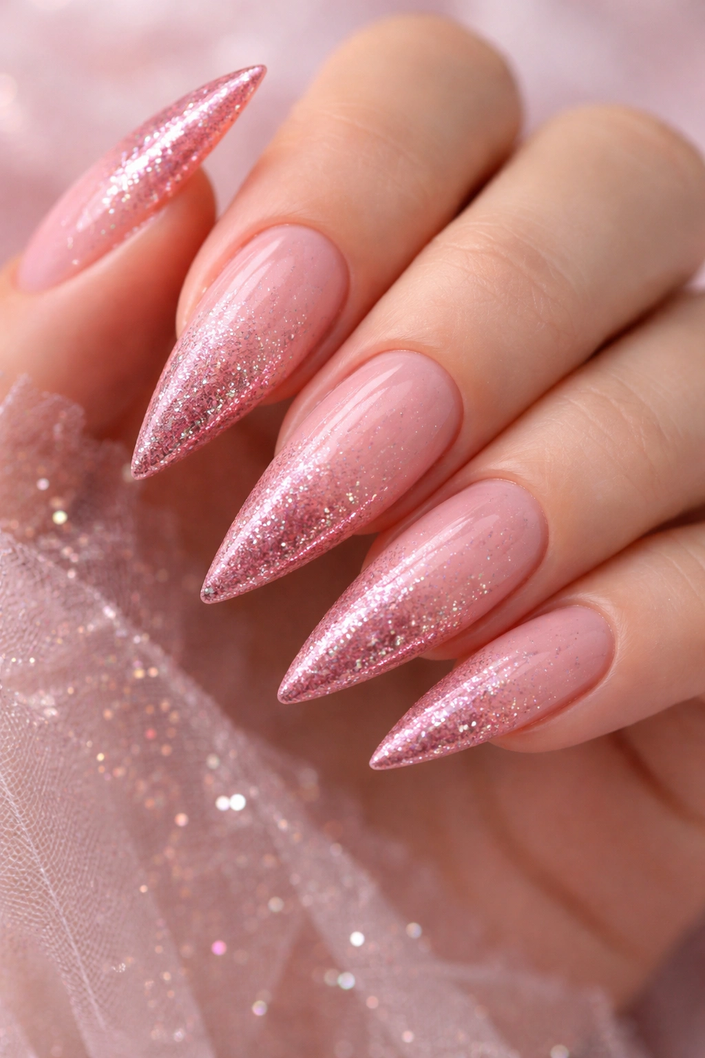 Close-up of rose pink gradient stiletto nails with sparkle
