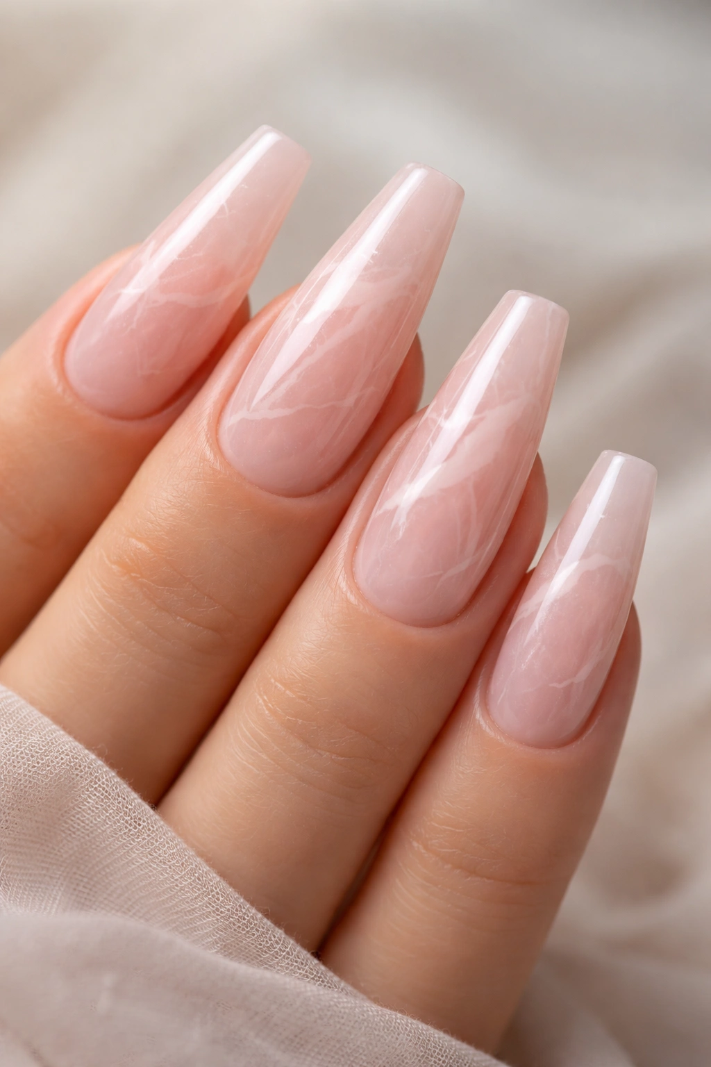 Close-up of rose quartz marble pink nails with delicate white veins.