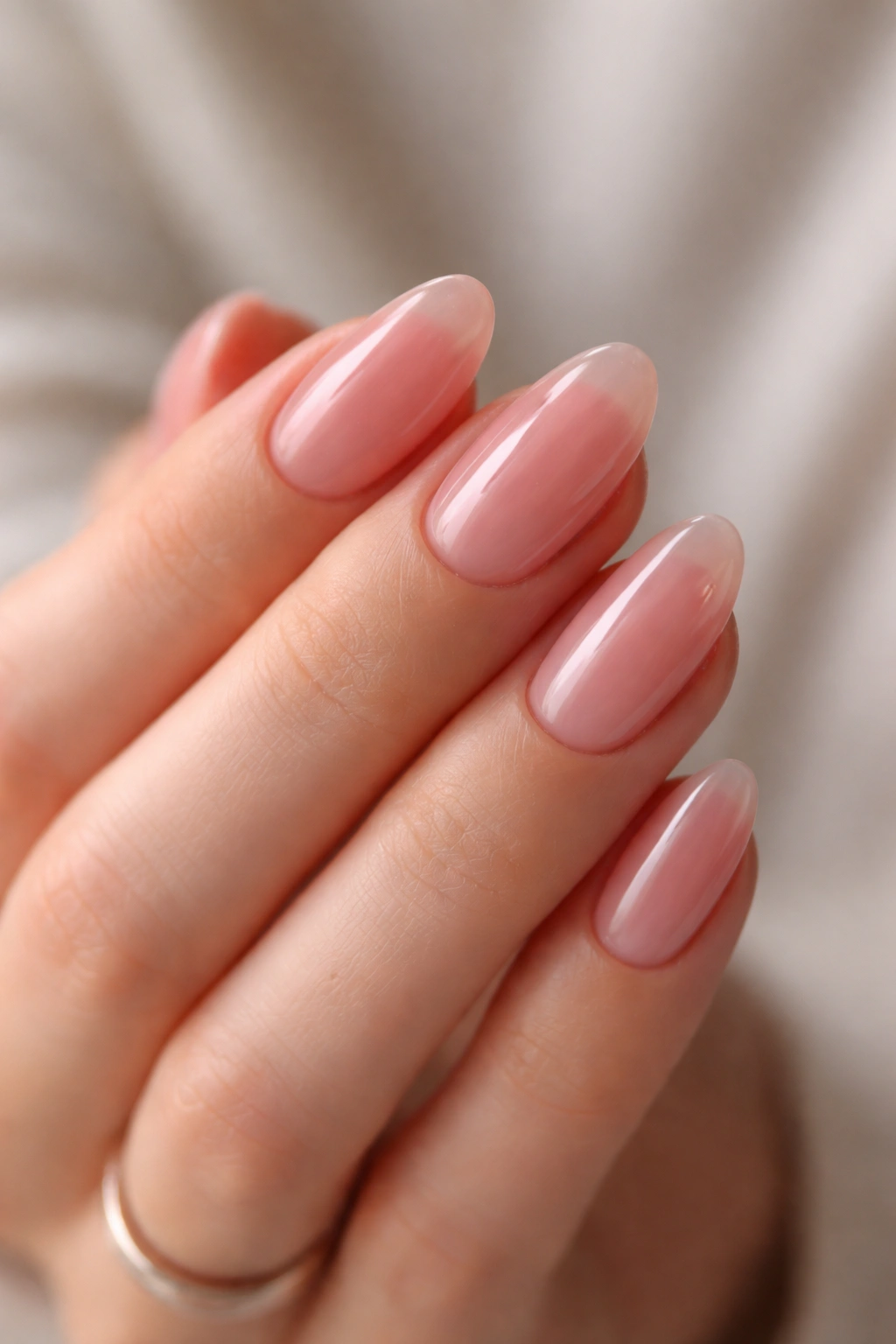 Close-up of short almond nails with translucent pink jelly finish showing depth
