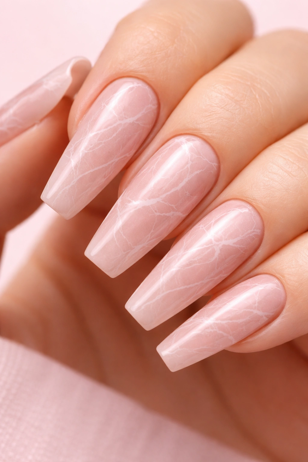 Close-up of rosy nude marble nails with fine white veining on ballerina nails
