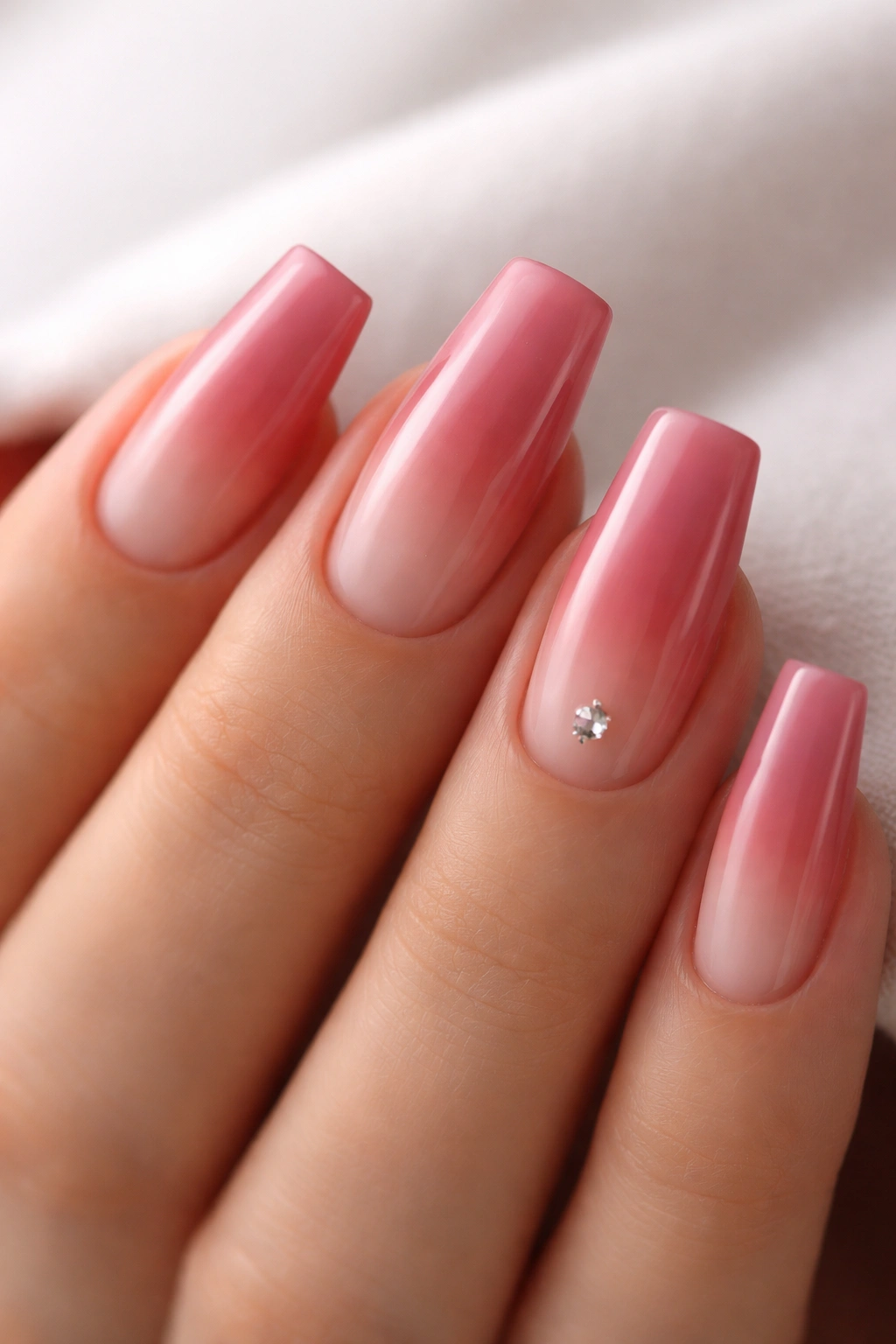 Close-up of deep rosy reverse ombre nails with a small crystal near the cuticle