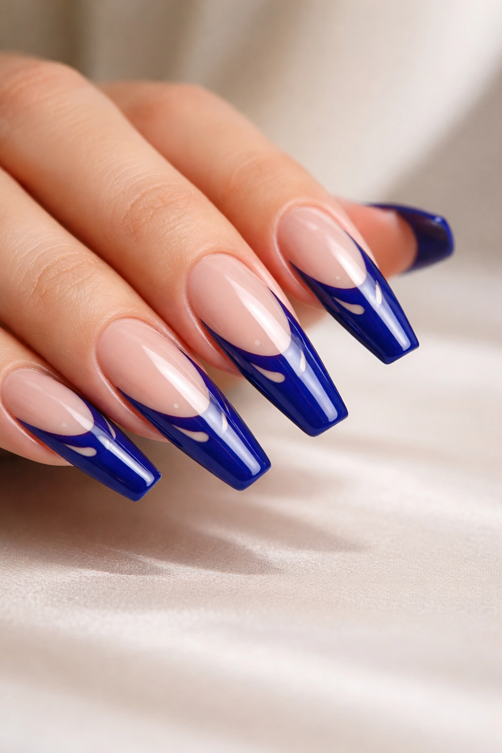 Close-up of deep royal blue cut-out tips with high-gloss finish on ballerina nails