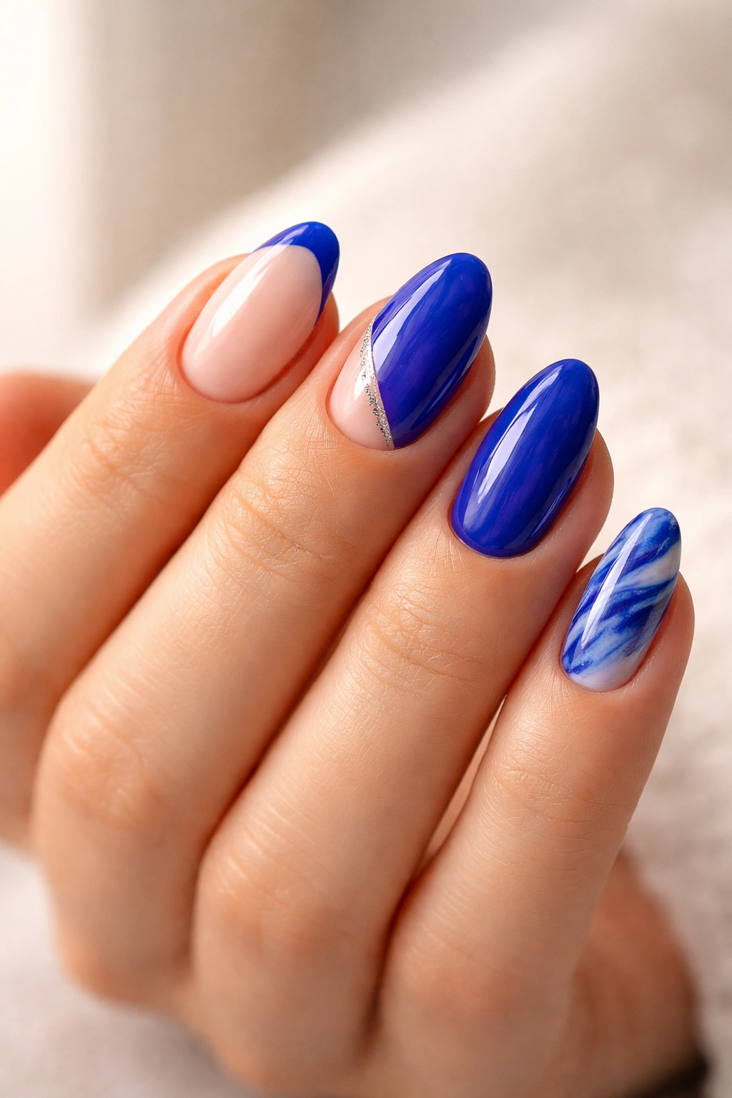 Hand showing multiple short almond nails with different royal blue designs to illustrate length-based choices