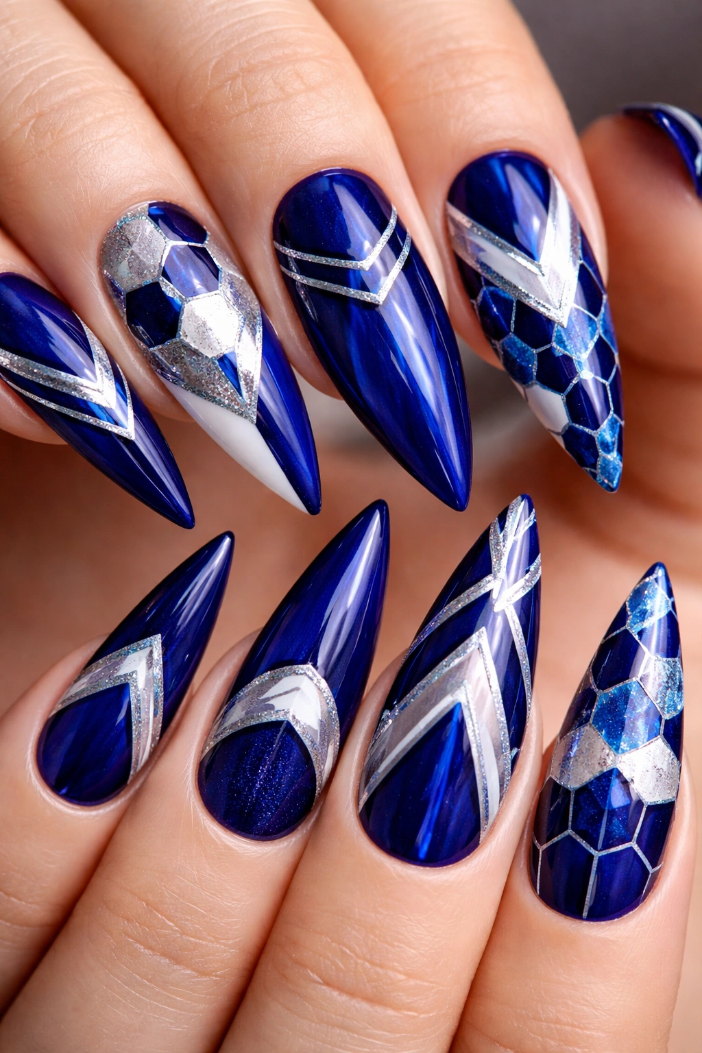 Close-up of stiletto nails with geometric royal blue patterns