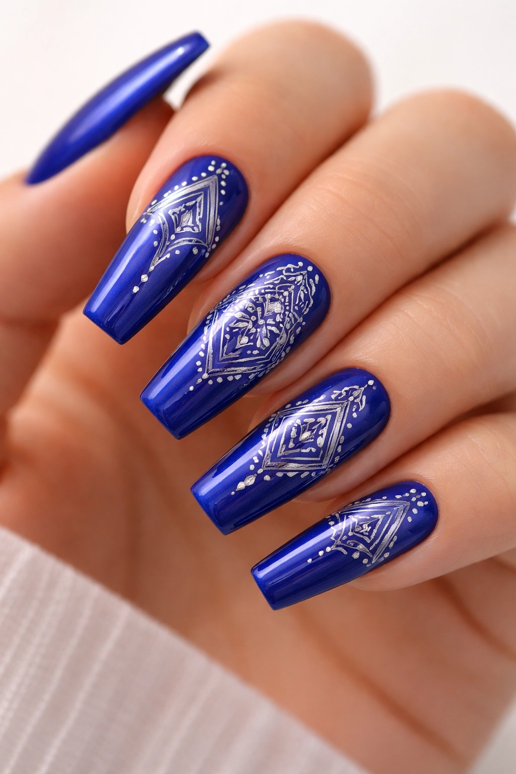 Close-up of royal blue nails with stamped geometric patterns