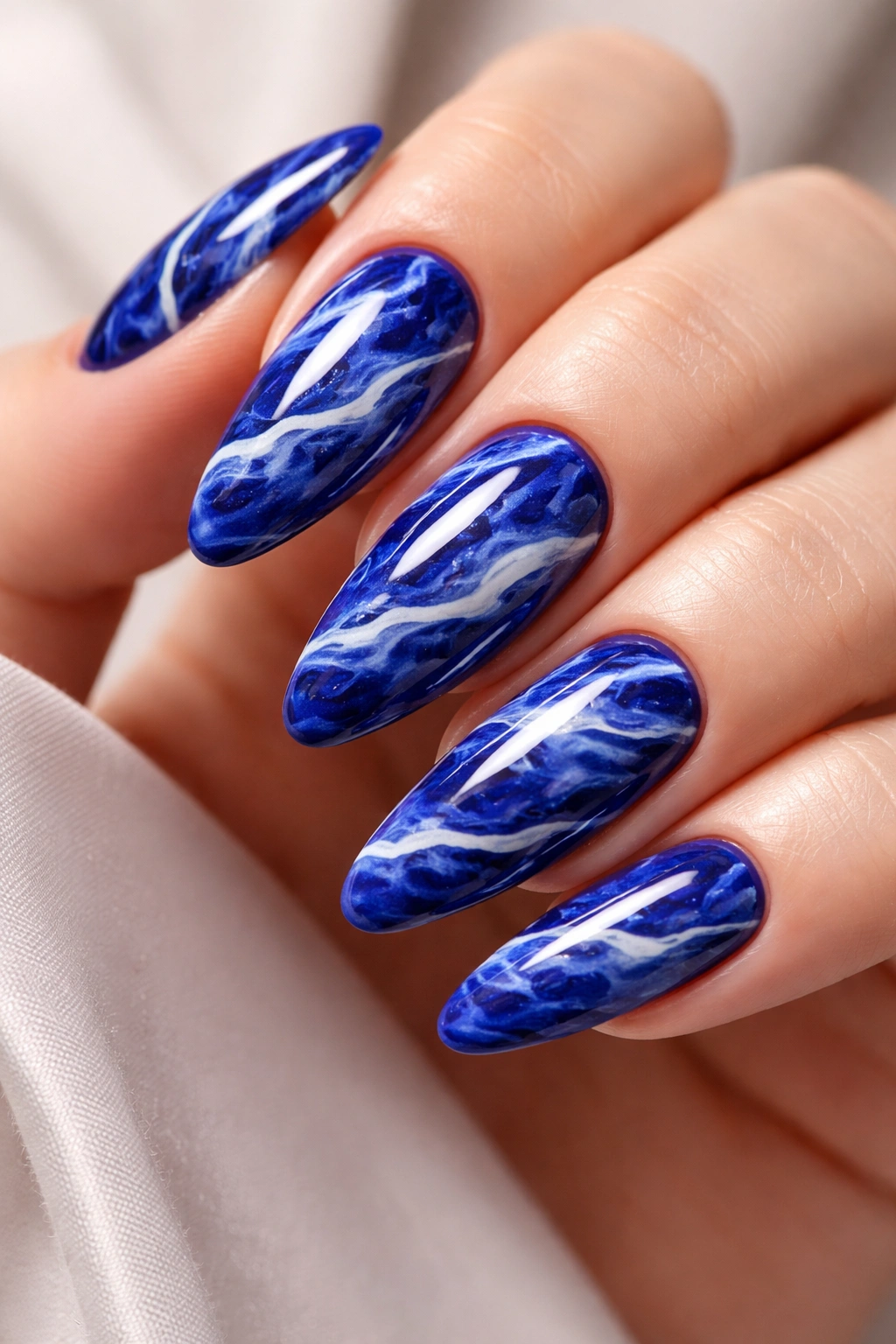 Royal blue marble nails with white veining in close-up