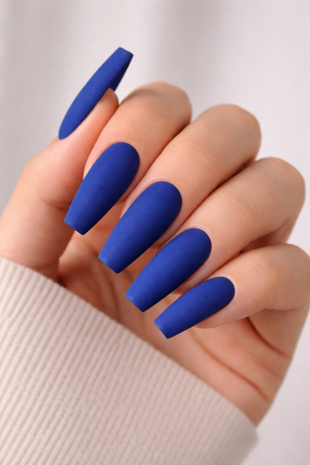 Close-up of coffin nails with royal blue velvet matte finish on a neutral background