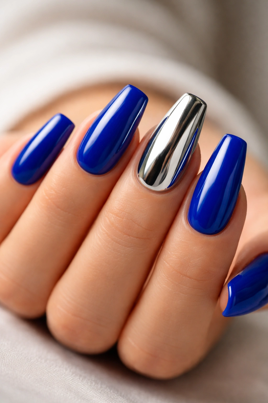 Nails with royal blue base and a chrome-coated accent nail