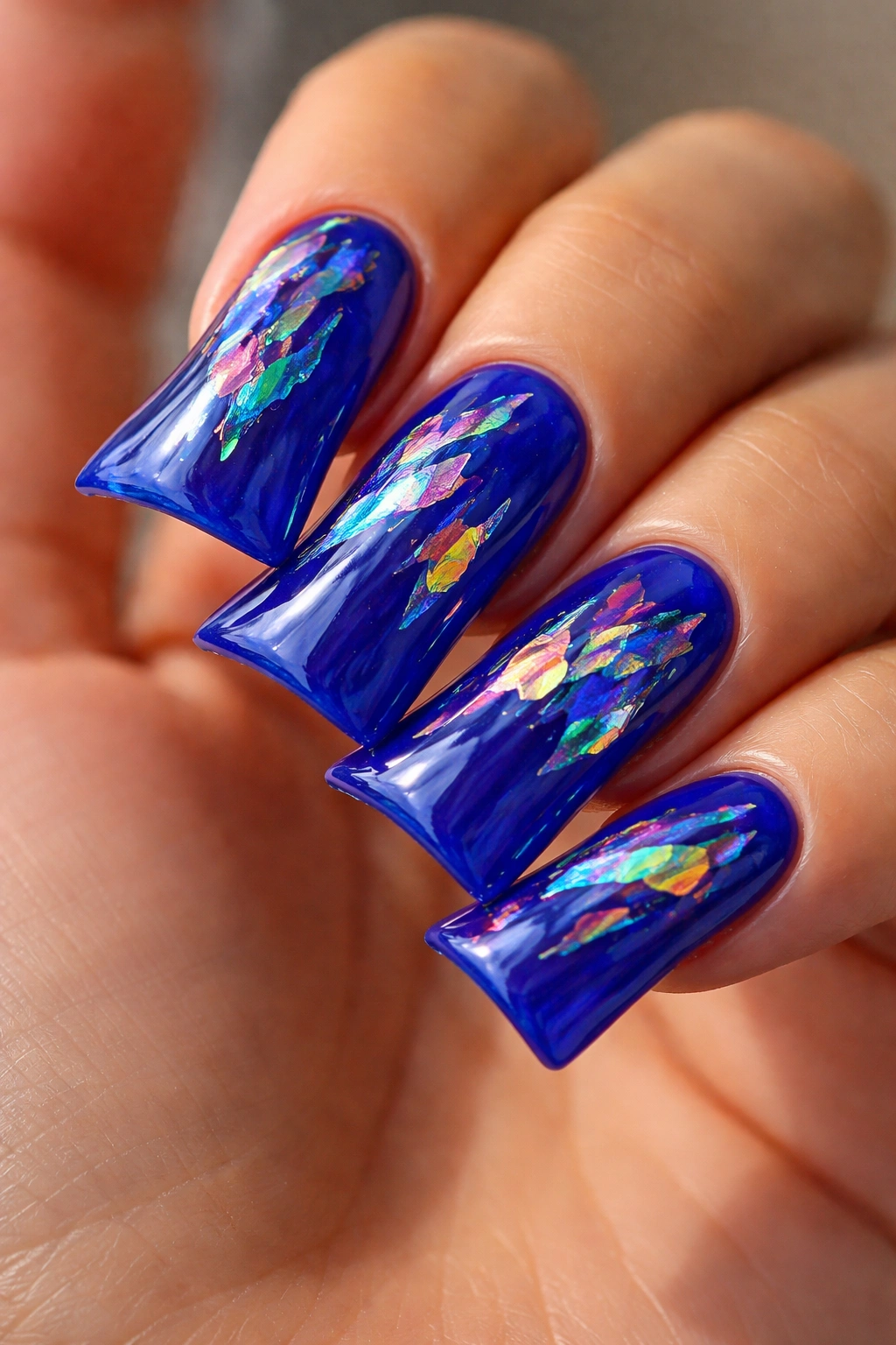 Close-up of royal blue duck nails with iridescent foil details