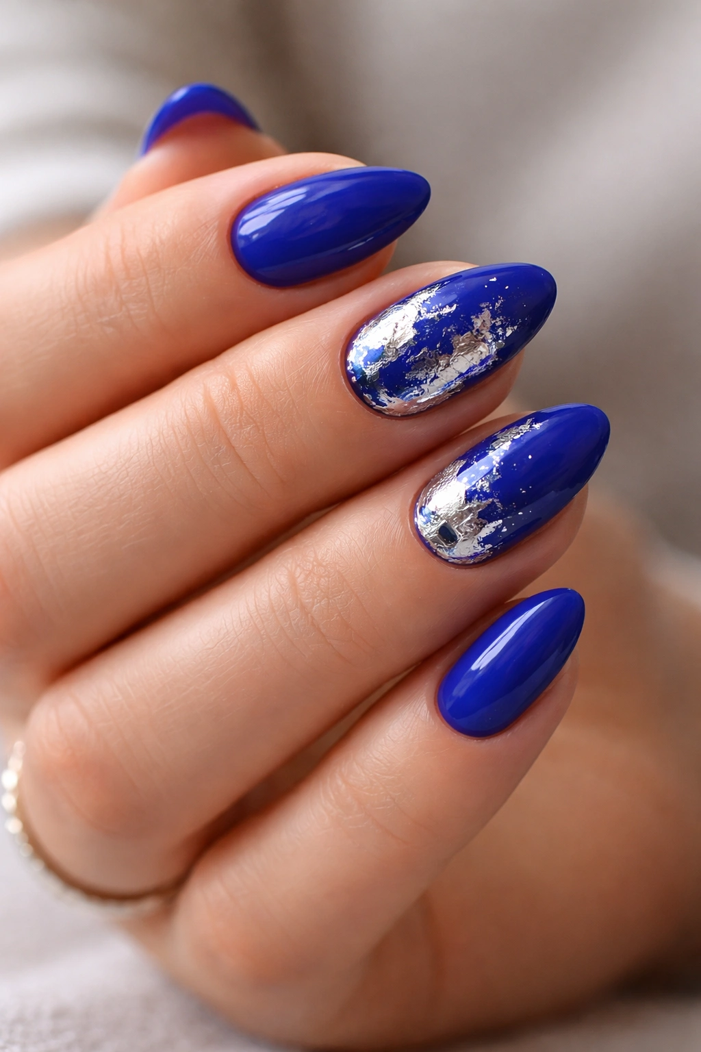 Close-up of royal blue nails with silver foil accents on selected nails