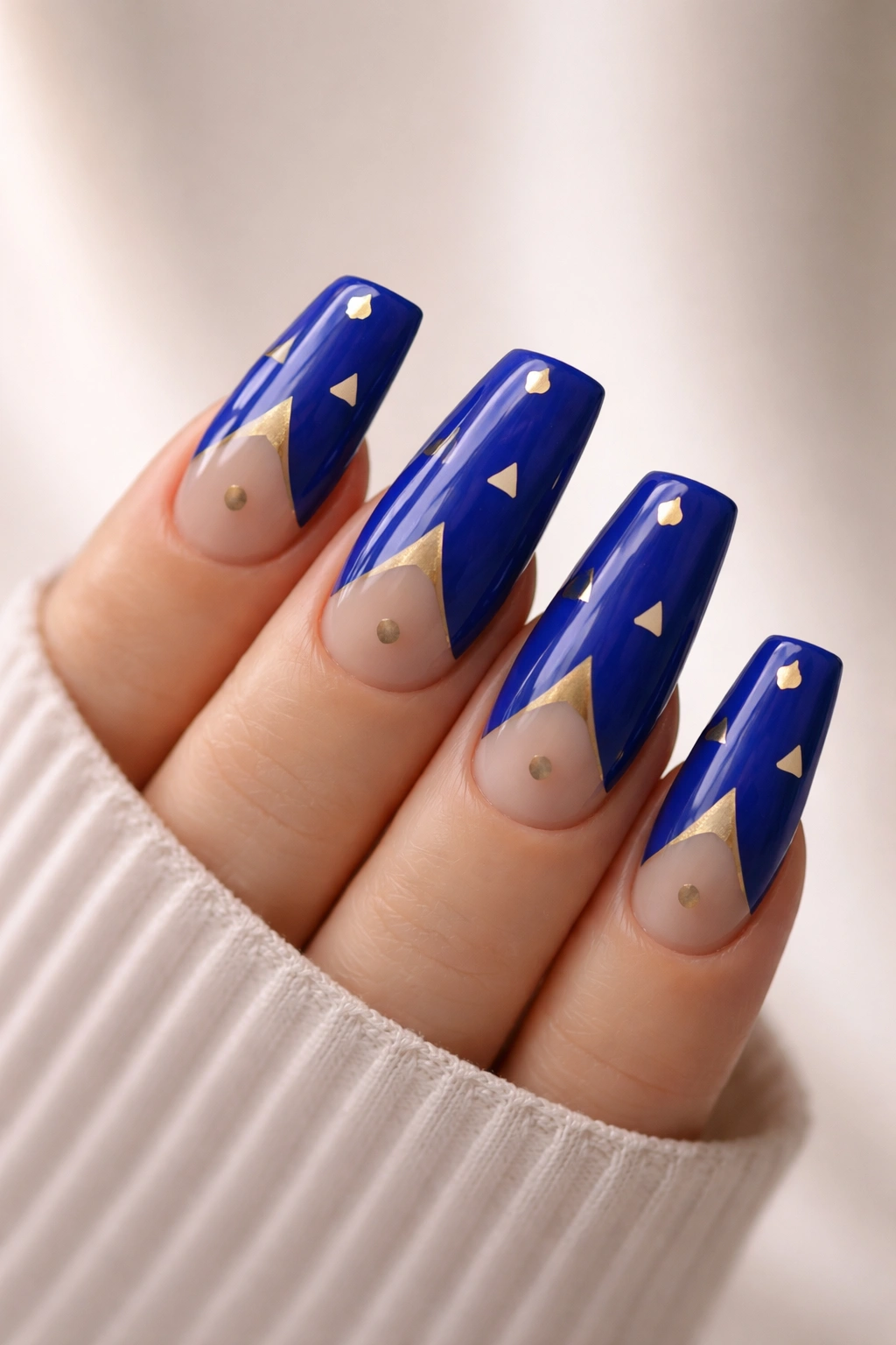 Close-up of royal blue duck nails with minimalist gold geometric shapes