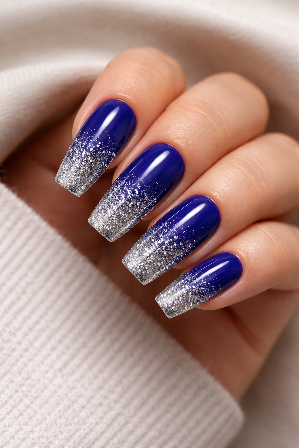 Nails showing royal blue base with silver glitter gradient at tips