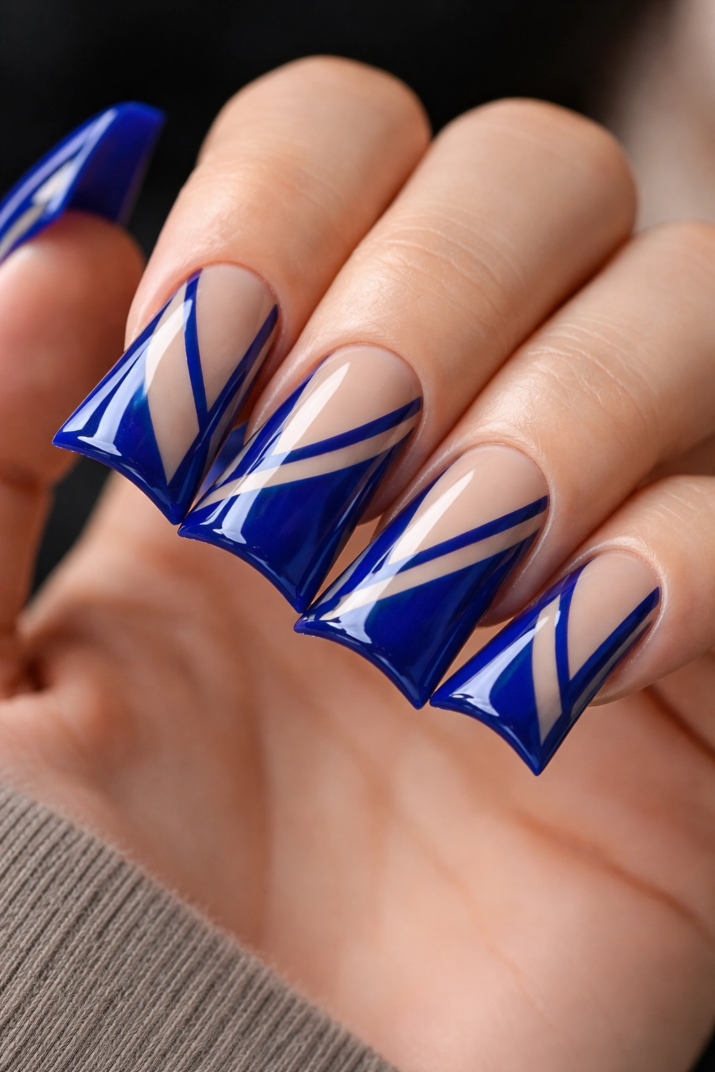 Duck nails with royal blue polish and negative-space line patterns.