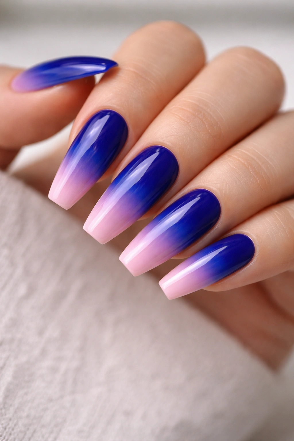 Close-up of royal blue coffin nails fading to pink tips in an ombre