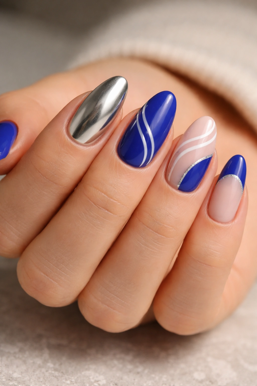 Short almond nails showing royal blue with silver, white lines, and milky nude pairings