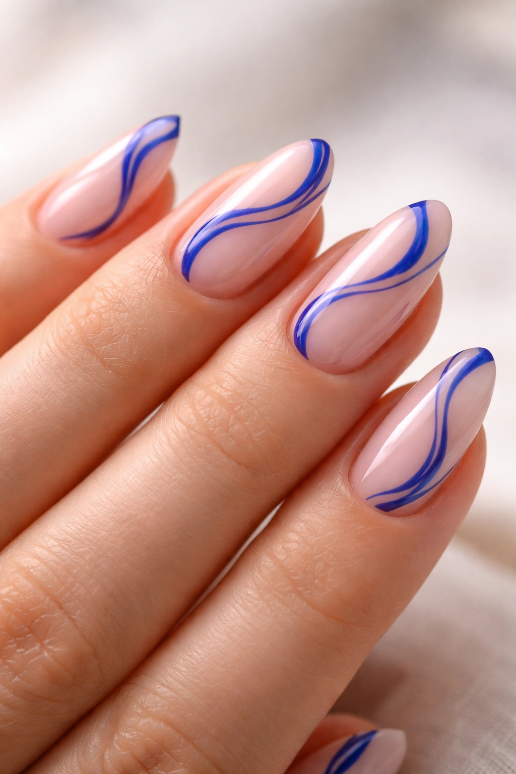 Short almond nails with blue swirl lines on sheer pink base