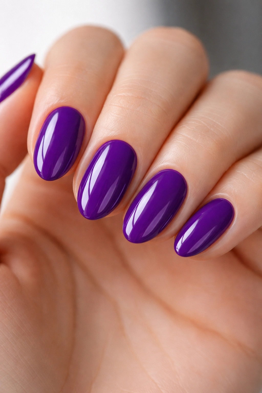 Close-up of short almond nails in royal purple with glossy top coat