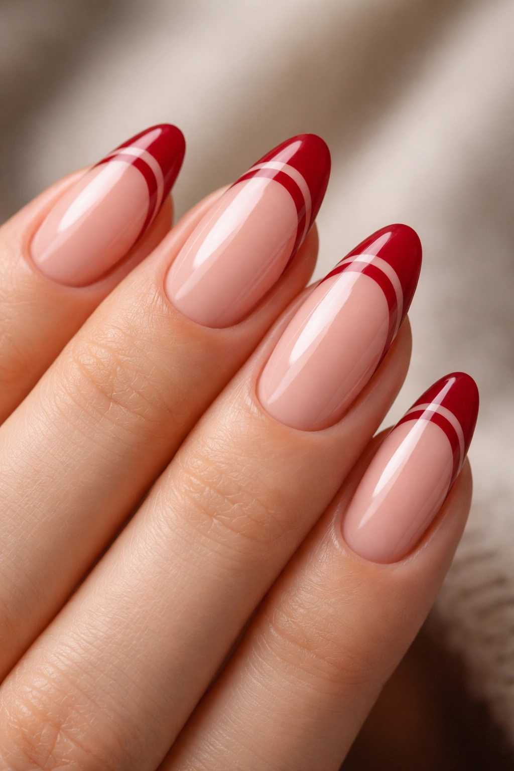 Close-up of short almond nails with double ruby red French lines
