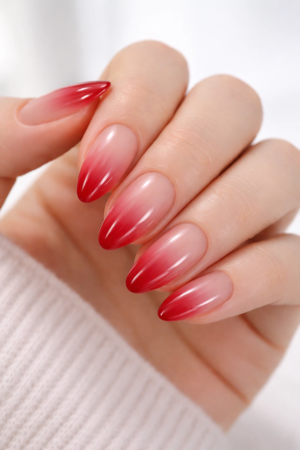 Almond nails with translucent ruby red fade on a hand
