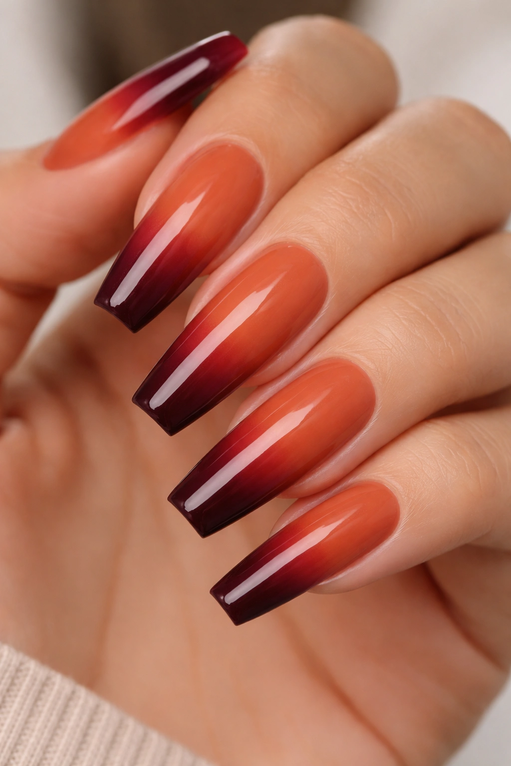 Close-up of long coffin nails with warm rust to burgundy ombre.