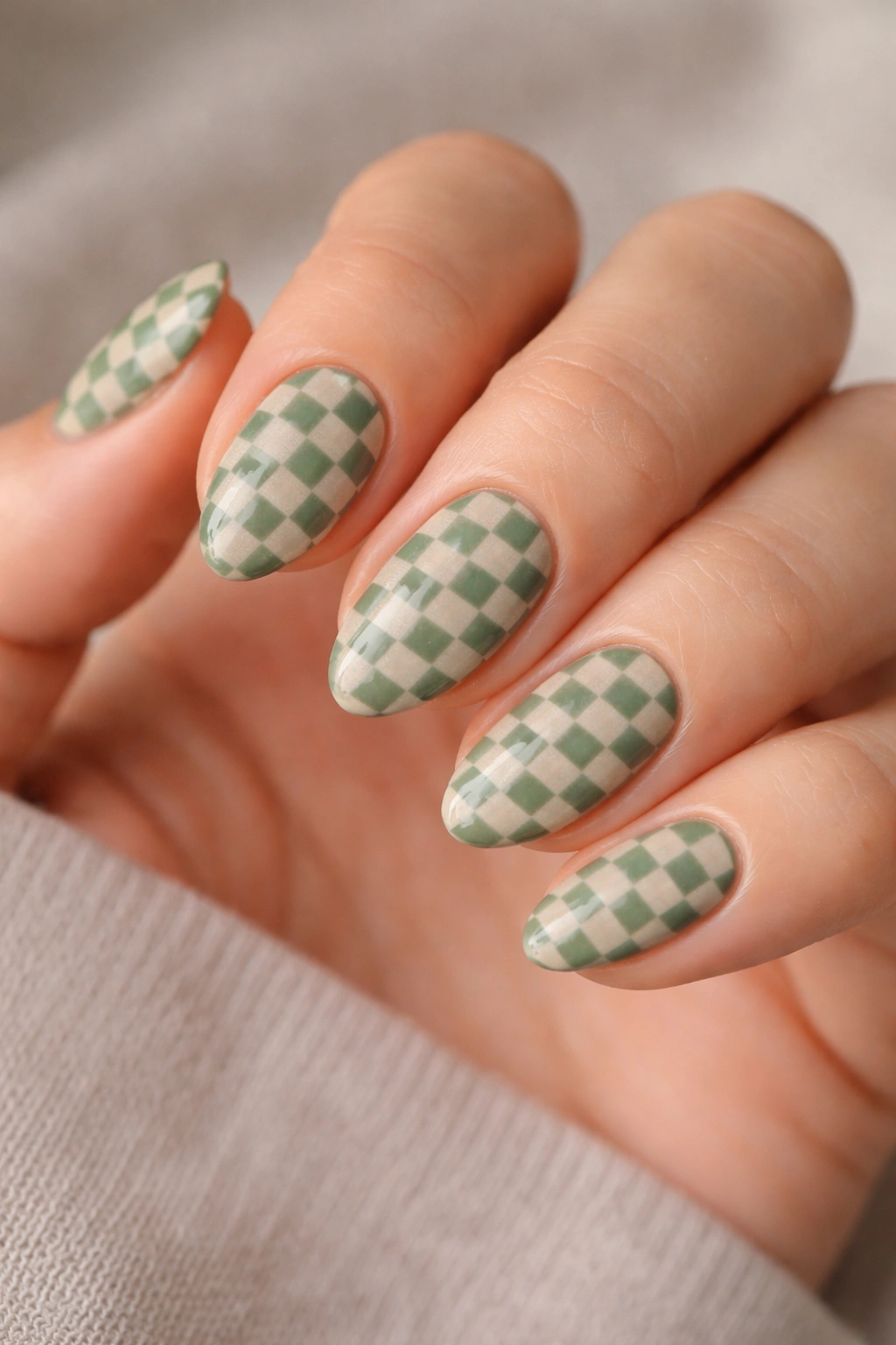 Close-up of sage green nails with beige checkerboard pattern